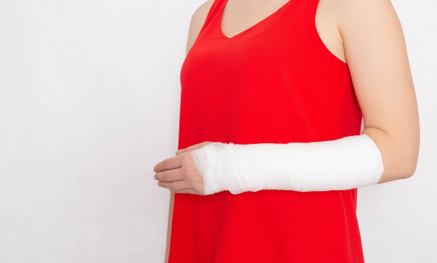 女孩穿着红色t恤，手臂骨折，绷带包扎得很紧，石膏贴在白色背景上。桡骨骨折治疗理念，复制空间图片下载