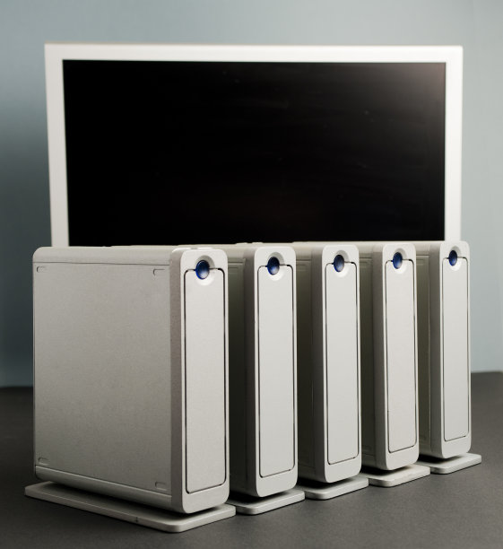 电脑文件概念，工作站由四个大型铝制硬盘组成，排列在黑色桌子上，部分视图银色显示器与黑色屏幕，蓝灰色墙壁背景，图片下载