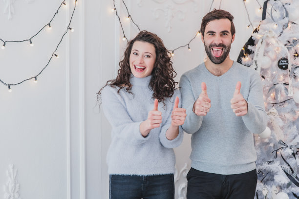 小两口竖起大拇指，露出舌头和微笑的新年照片。图片下载