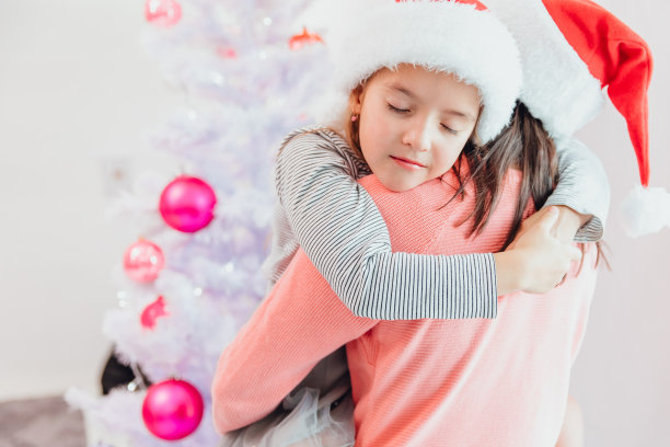 慈爱的母女在圣诞树旁拥抱，看起来美极了。图片下载
