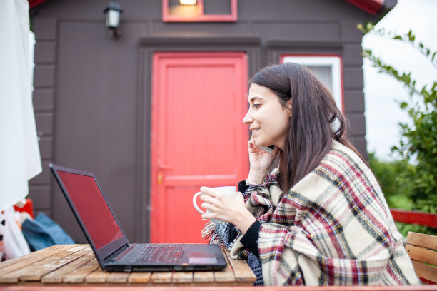 自由职业者女孩，拿着咖啡和笔记本在花园的门廊上。库存图片图片下载