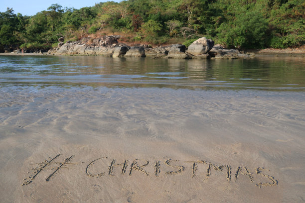 图片的标签标签写在阳光明媚的海滩上，圣诞节的单词写在沙滩上，背景是岩石和泻湖，Palolem海滩，印度果阿，概念社交媒体照片的手写在金色的沙子与现代标签前缀图片下载