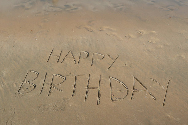 图片的标签标签写在阳光沙滩上的生日快乐的单词写在沙滩上，Palolem海滩，印度果阿，概念社交媒体照片的手写在金色的沙子与现代标签前缀图片下载