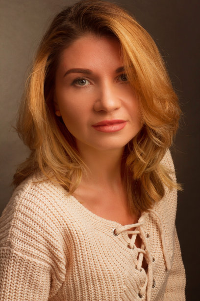 一个中年金发女人的肖像在浅灰色的背景白色衣服。图片下载