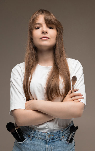 自信的造型师，满口袋的化妆刷在一个黑暗的背景图片下载