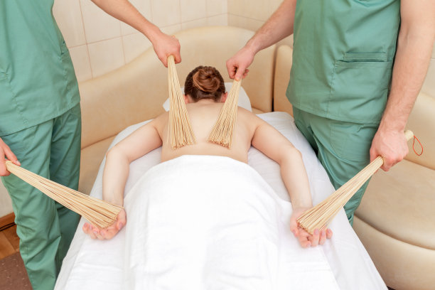 接受竹扫帚按摩的女人。图片下载