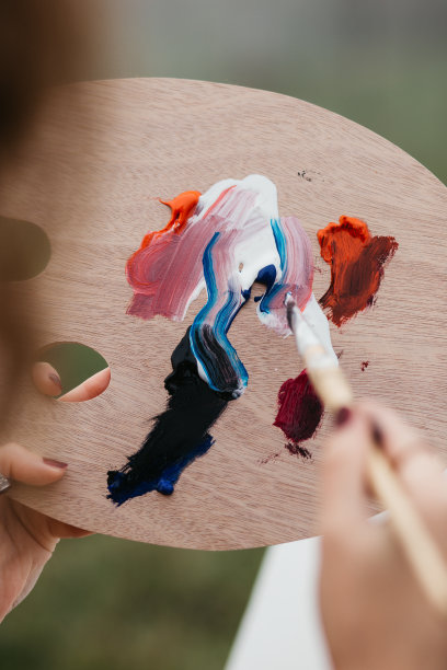 近距离的照片年轻的女艺术家工作在绘画户外。她拿着油画颜料，艺术家的画笔，帆布和调色板。她在调色板上调色。手关闭。图片下载