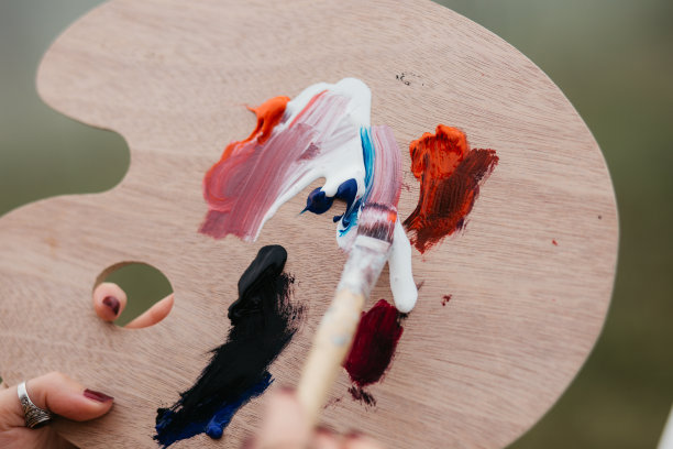 近距离的照片年轻的女艺术家工作在绘画户外。她拿着油画颜料，艺术家的画笔，帆布和调色板。她在调色板上调色。手关闭。图片下载