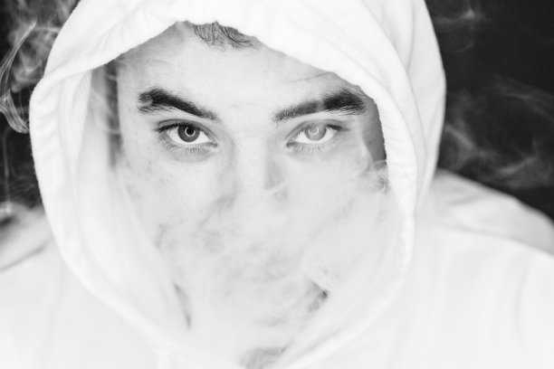 一个抽烟的年轻人的肖像，摄影，黑白，特写。Led圈反射在眼睛里图片下载