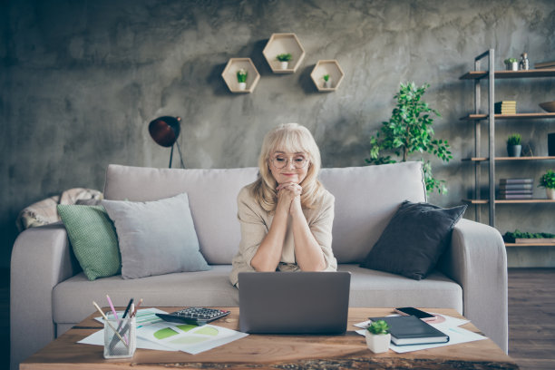 照片惊人的白发苍苍的老奶奶使用笔记本看在线大师班商务讲座课讲skype同事坐在沙发房间办公室室内图片下载