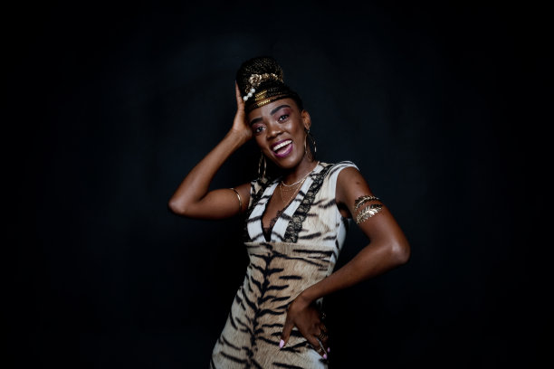 非裔美国女性穿着裙子站在黑色背景前图片下载