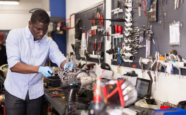 非裔美国工人在车库里修理摩托车引擎图片下载
