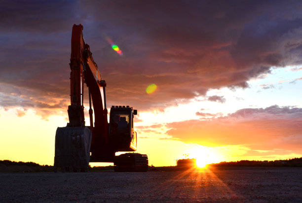 在可怕的日落背景下，建筑工地上的挖掘机图片下载