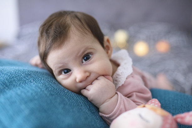 刚出生的女婴在床上玩玩具图片下载