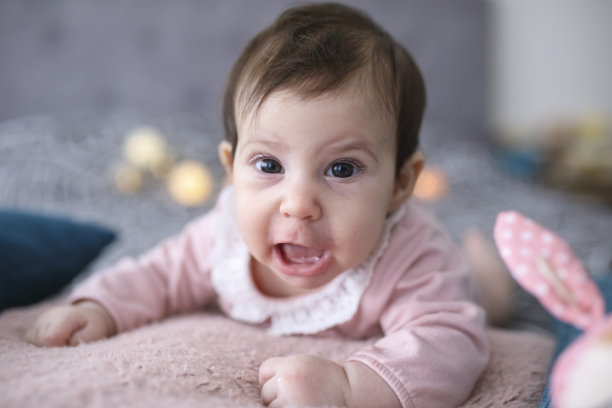 刚出生的女婴在床上玩玩具图片下载