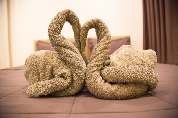 浪漫的卧室内部，亲吻天鹅折纸毛巾装饰在酒店房间的床上为新婚夫妇。采购产品婚礼，情人节，周年纪念，蜜月，工艺，住宿，爱和象征的概念图片下载