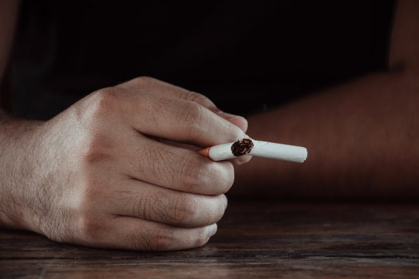 一个男性手握香烟的特写，并打破一根香烟图片下载