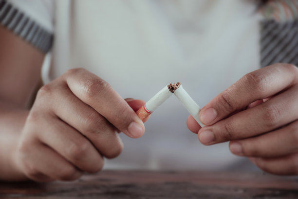 一个男性手握香烟的特写，并打破一根香烟图片下载