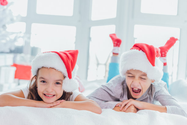 近距离拍摄的兄弟姐妹肩并肩在床上靠近杉树。疲惫的男孩在打哈欠，几乎要睡着了。图片下载