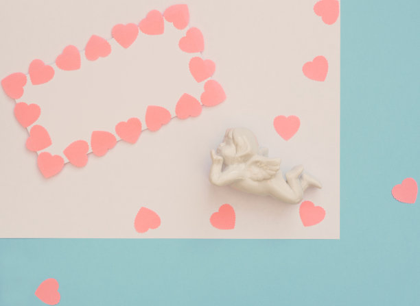 白色的丘比特，与粉红色的心框架在蓝色的背景空白页。情人节问候，请帖。2、生日、婚礼、爱情、幸福概念。平铺与复制空间的文本。图片下载