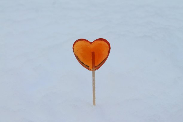 红色的心形棒棒糖在冬天的雪地里图片下载