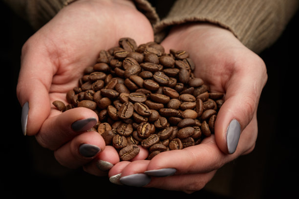 女人的手里捧着一把咖啡豆。图片下载