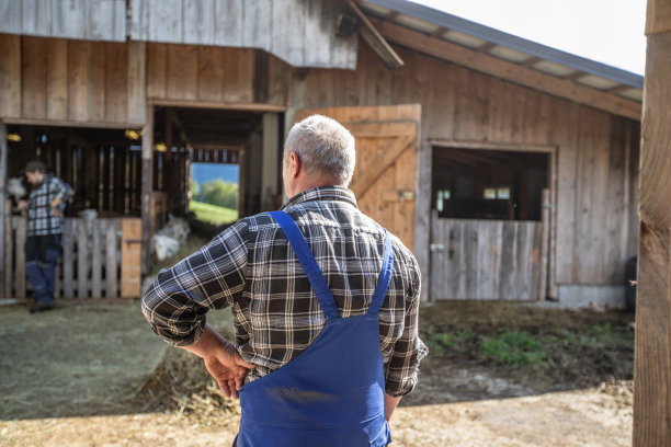 老农民站在马厩前，手放在臀部-股票照片图片下载