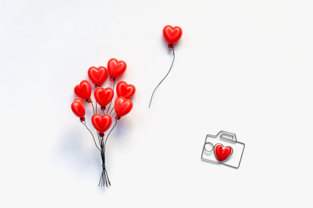 红色的心形气球与抽象的相机在白色的背景。图片下载