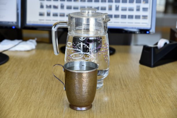 办公室桌子上装有玻璃水罐的纯铜马克杯图片下载