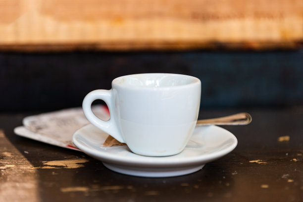 意大利咖啡早餐的盘子碟子和背景桌子上的浓缩卡布奇诺咖啡杯的微距特写图片下载