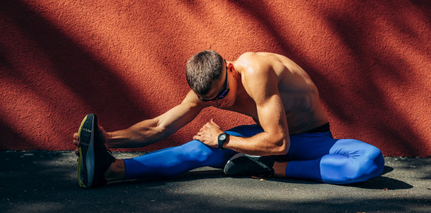 健身者在户外靠在混凝土墙上伸展身体。男运动员在户外锻炼后伸展身体。运动与人的理念。为你的文本复制空间图片下载