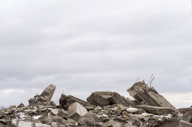 一堆巨大的灰色混凝土碎片和突出的配件映衬着多云的天空。图片下载