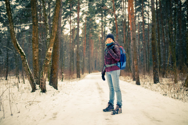 照片微笑的女人戴着帽子和背包在冬天的森林图片下载