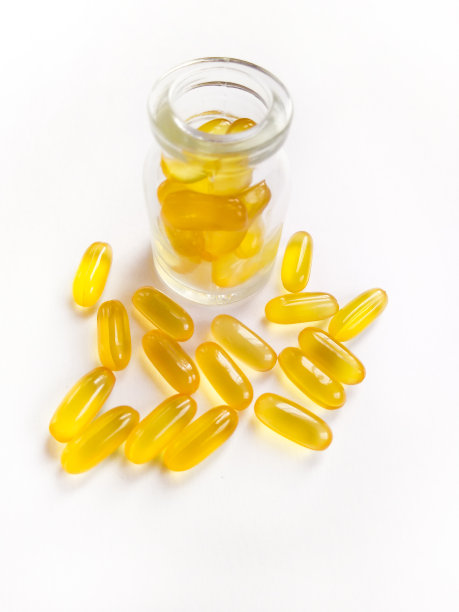 鱼油胶囊在白色背景下从瓶中溢出。图片下载