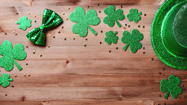 圣帕特里克节贺卡，带有传统符号，三叶草，绿色服装。绿色的帽子，领结，圣帕特里克节三叶草，金色的纸屑木制背景，复制空间图片下载