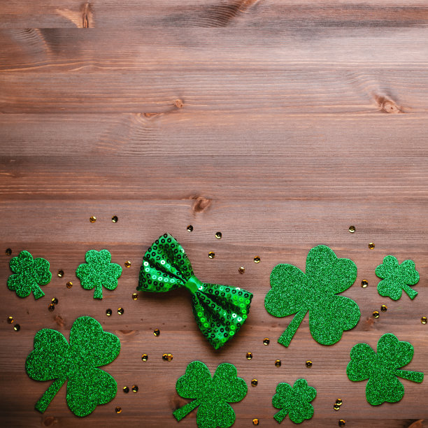 圣帕特里克节贺卡，带有传统符号，三叶草，绿色服装。绿色的帽子，领结，圣帕特里克节三叶草，金色的纸屑木制背景，复制空间图片下载