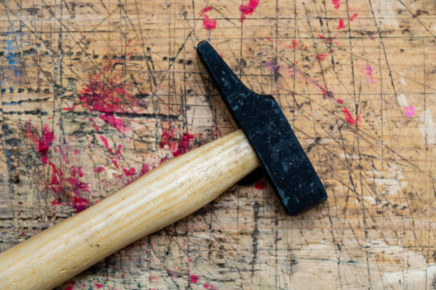 铁锤与木柄在使用垃圾污染的木制长凳表面。图片下载