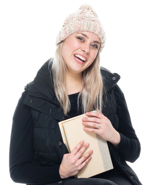 白人女学生蹲下穿着毛衣，拿着书图片下载