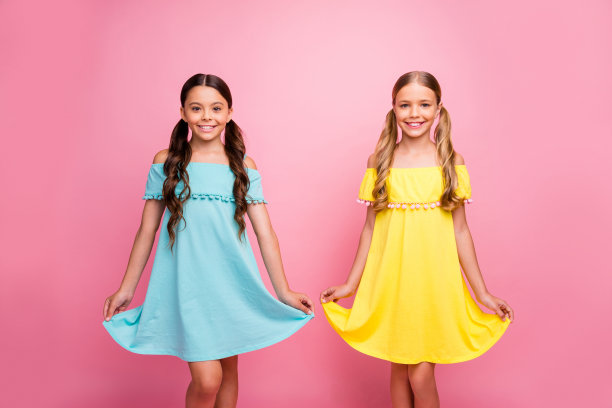 两人的照片美丽的小学校女生同学一起度过暑假可爱甜蜜的街道看穿蓝色的黄色连衣裙孤立的粉红色背景图片下载