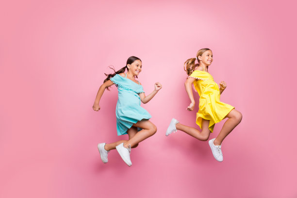 全身档案照片的两个友谊小女士模特跳高匆忙回家暑假开始穿蓝色的黄色连衣裙孤立的粉红色背景图片下载