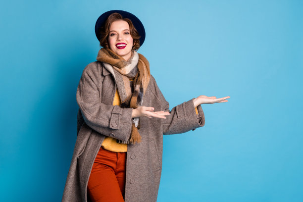现在市民在这里购物。漂亮的女士在国外工作的照片，导游指示手臂历史建筑穿休闲长灰色外套围巾裤子帽子孤立的蓝色背景图片下载