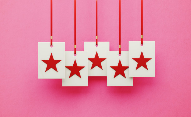 白色方块上的红星悬挂在粉红色背景上的红丝带上图片下载