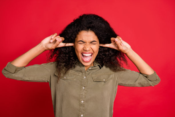照片上的尖叫，疯狂的愤怒的模特穿着绿色衬衫闭上她的耳朵哭孤立的色彩背景图片下载