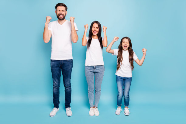 funky三个人的全身照片冠军妈妈，爸爸，孩子深色头发庆祝胜利举起拳头尖叫耶穿白色t恤牛仔牛仔裤运动鞋孤立的蓝色背景图片下载
