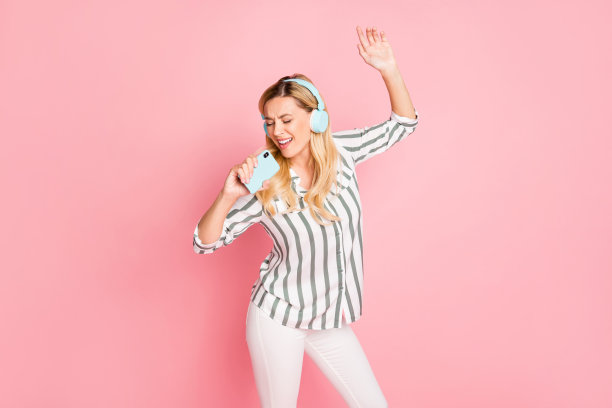 照片的愉快积极有吸引力的女人唱歌到电话想象这是麦克风微笑牙齿灵感来自著名流行歌手在白色裤子孤立的柔和的颜色背景图片下载