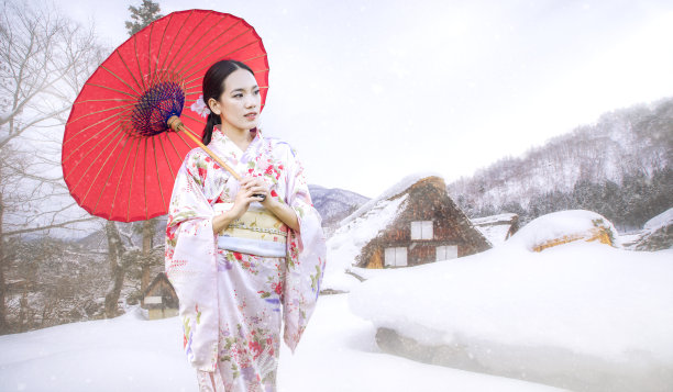 亚洲女性游客。一个日本女孩拿着一把红伞。白川是日本岐阜县的一个村庄，穿着日本传统和服的美丽女性。图片下载