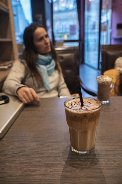 在咖啡桌上用笔记本电脑工作后喝冰咖啡的漂亮年轻女人。图片下载