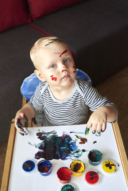 一个脏兮兮的小男孩用手指画画画。图片下载