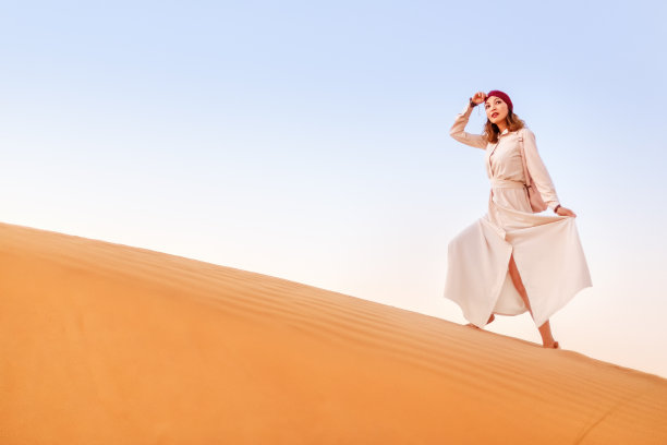 戴着头巾的快乐亚洲女人在撒哈拉沙漠旅行。冒险和生活体验概念图片下载
