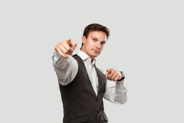 穿着白色衬衫和灰色背心的年轻人指着他的手指对着摄像机图片下载